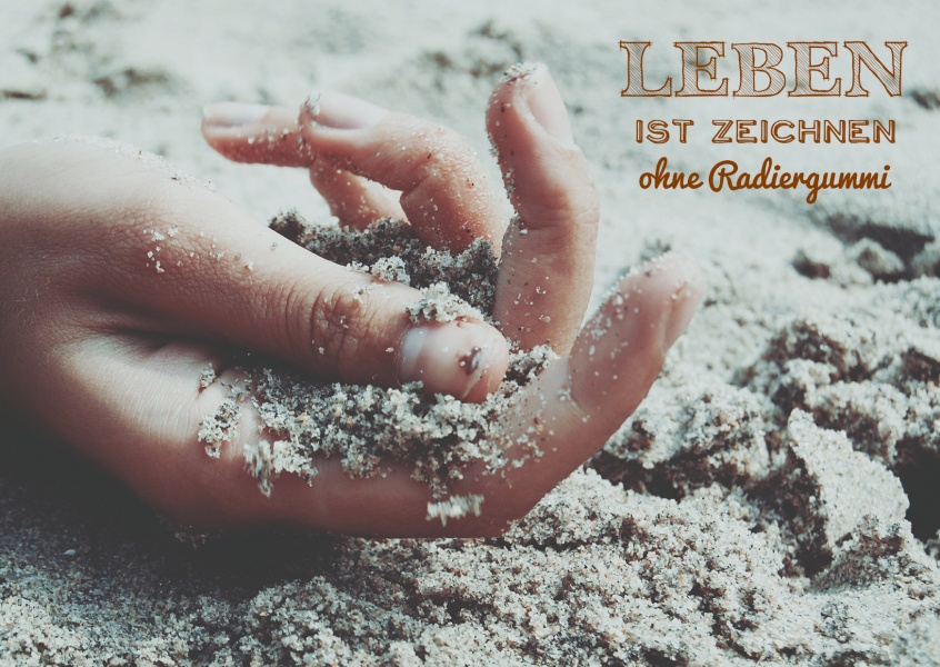 Bild hand im sand und der spruch das leben ist zeichnen ohne radiergummi