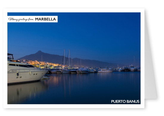 Photo of Puerto Banus in Marbella at night with mountains in the background