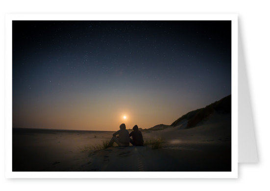 zwei Freunde mit Kapuze sitzen nachts in der Wüste