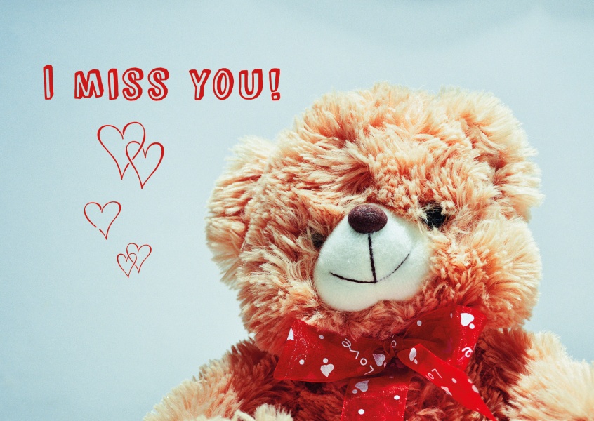 Flauschiger Stoff-Teddy mit roter Schleife, illustrierten Herzen und dem Spruch I miss you