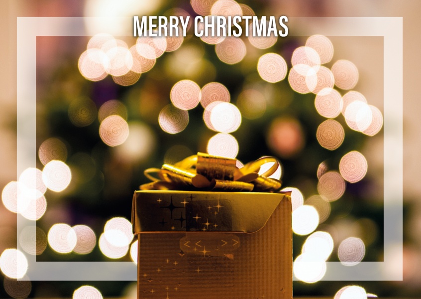 Christmas greeting card with a present in focus and lights in the backround