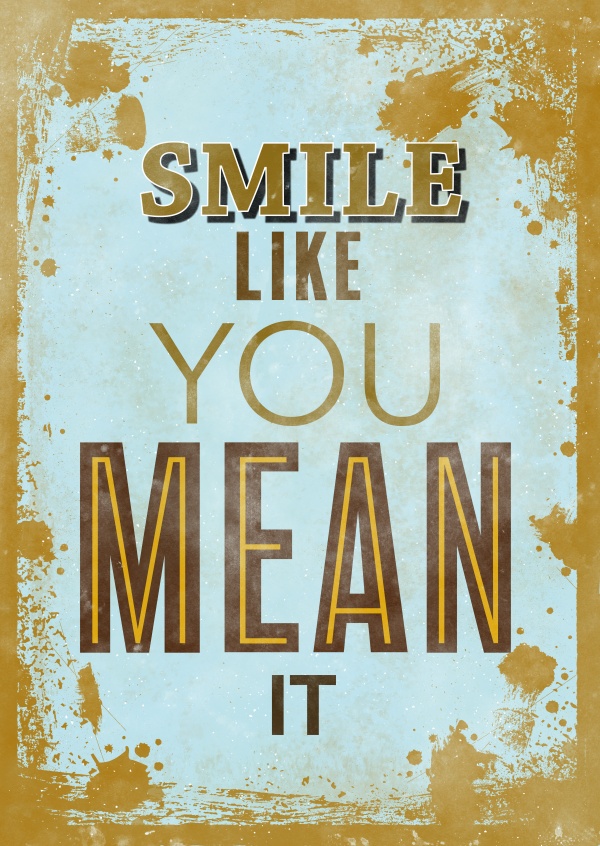 Saying smile like you mean it in different fonts and colours on a bright background with splash pattern
