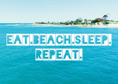 Postkarte mit dem schriftzug  eat. beach. sleep. repeat. in weiß auf einem foto mit strand und meer.