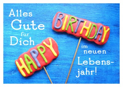 foto von süßigkeiten gebacken mit bunter happy birthday glasur auf blauem holztisch