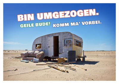 Foto von altem Wohnwagen in der Wüste mit Spruch zur neuen Wohnung–mypostcard