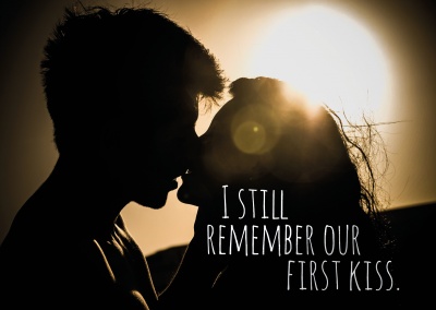 Leidenschaftlich küssendes Pärchen im Sonnenuntergang mit den Worten I still remember our first kiss