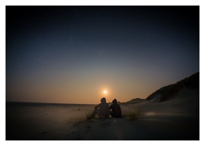 zwei Freunde mit Kapuze sitzen nachts in der Wüste